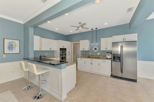 kitchen featuring dark countertops, a peninsula, appliances with stainless steel finishes, and white cabinets