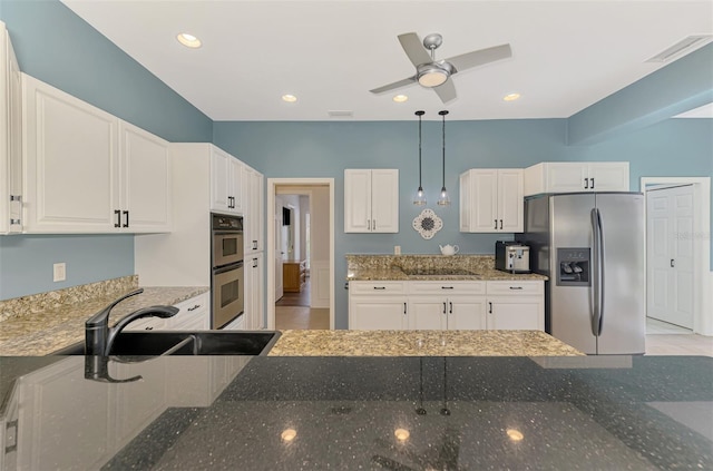 kitchen with pendant lighting, appliances with stainless steel finishes, white cabinetry, a sink, and dark stone counters