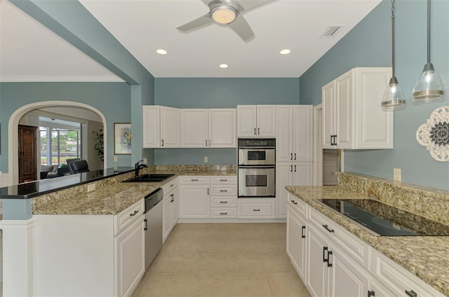 kitchen with pendant lighting, appliances with stainless steel finishes, white cabinets, a sink, and dark stone countertops