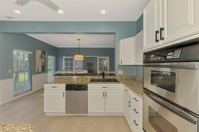 kitchen featuring stainless steel appliances, a wainscoted wall, white cabinets, and a peninsula