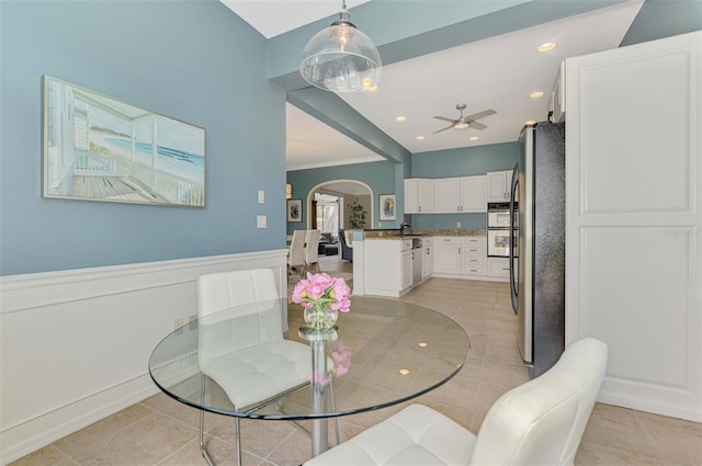 dining space featuring arched walkways, a wainscoted wall, light tile patterned floors, recessed lighting, and ceiling fan