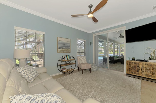 living area with ornamental molding, visible vents, ceiling fan, and baseboards