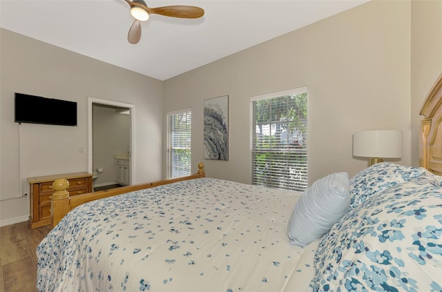 bedroom featuring light wood finished floors, ceiling fan, baseboards, and connected bathroom