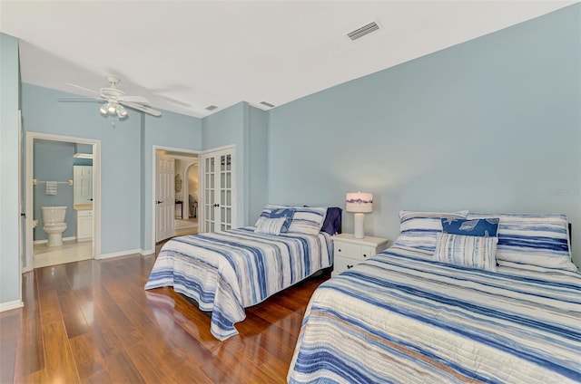 bedroom with ensuite bathroom, dark wood-style flooring, visible vents, baseboards, and french doors