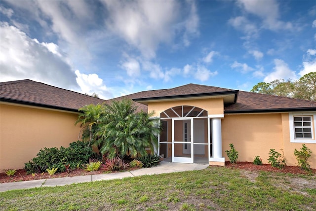 back of property with a lawn and a sunroom