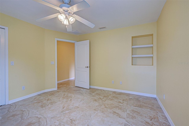 spare room featuring ceiling fan and built in shelves