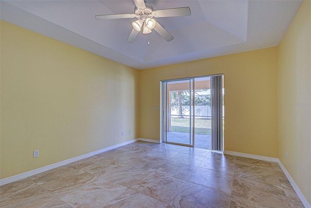 empty room featuring a raised ceiling and ceiling fan