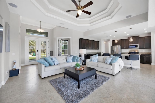 living room featuring ornamental molding, a tray ceiling, french doors, and light tile patterned floors