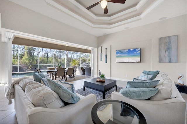 living room featuring a raised ceiling, a ceiling fan, a sunroom, ornamental molding, and light tile patterned flooring