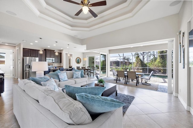 living area with ornamental molding, a raised ceiling, light tile patterned flooring, and a high ceiling