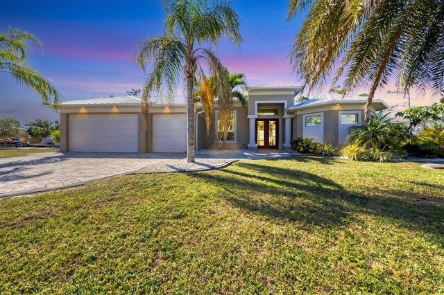 mid-century inspired home featuring metal roof, an attached garage, decorative driveway, french doors, and stucco siding