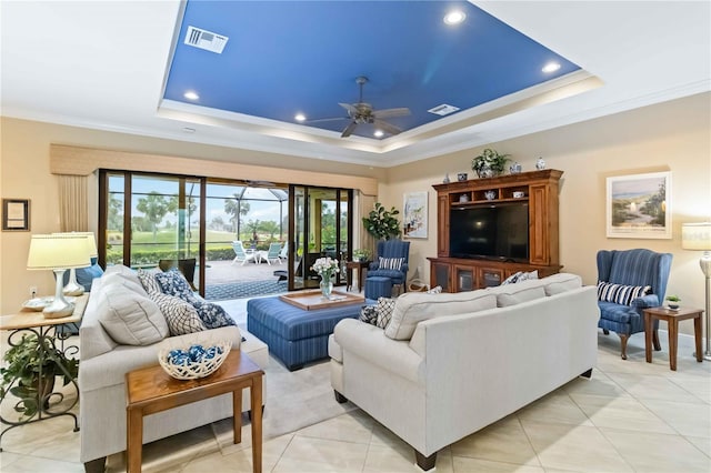 living area with a tray ceiling, visible vents, and crown molding