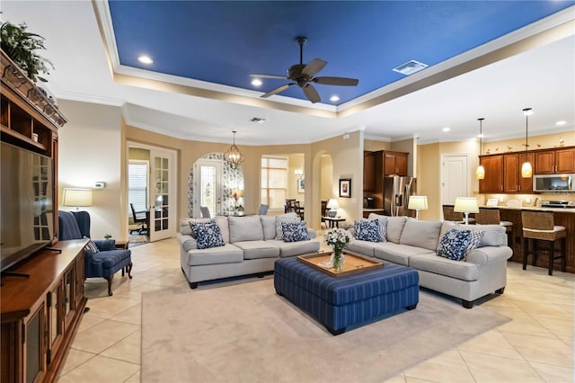 living room featuring a tray ceiling, visible vents, arched walkways, and light tile patterned floors