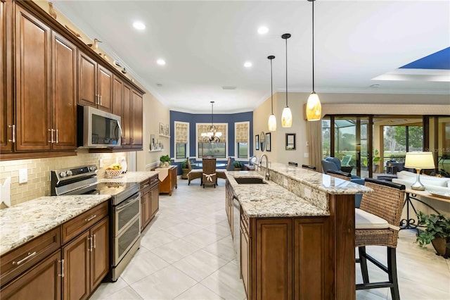 kitchen featuring open floor plan, appliances with stainless steel finishes, a sink, and pendant lighting