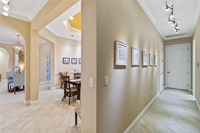 hallway with arched walkways, ornamental molding, light tile patterned floors, and baseboards