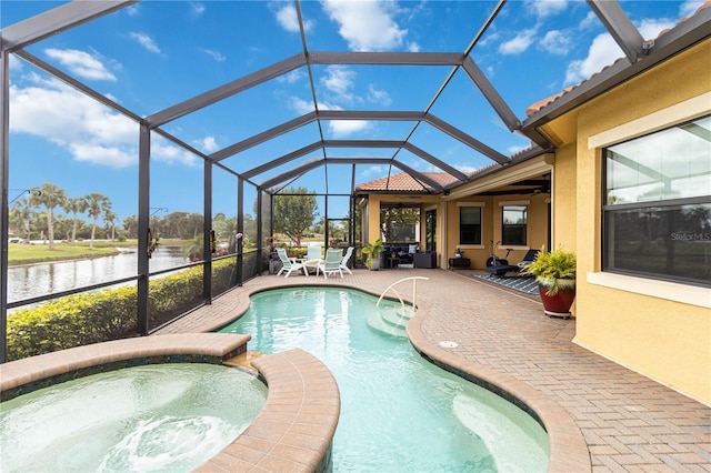 view of pool featuring a pool with connected hot tub, a water view, a ceiling fan, a patio area, and glass enclosure