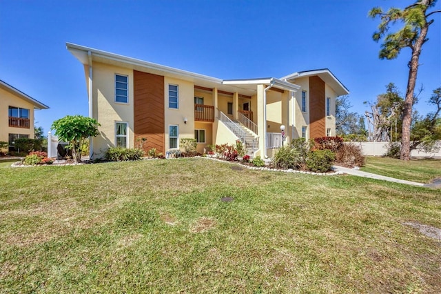 view of front of house featuring a front yard, stairway, and stucco siding