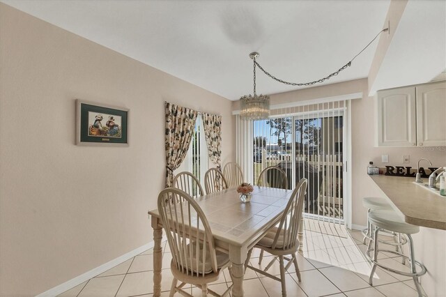 dining space featuring light tile patterned floors, baseboards, and a chandelier