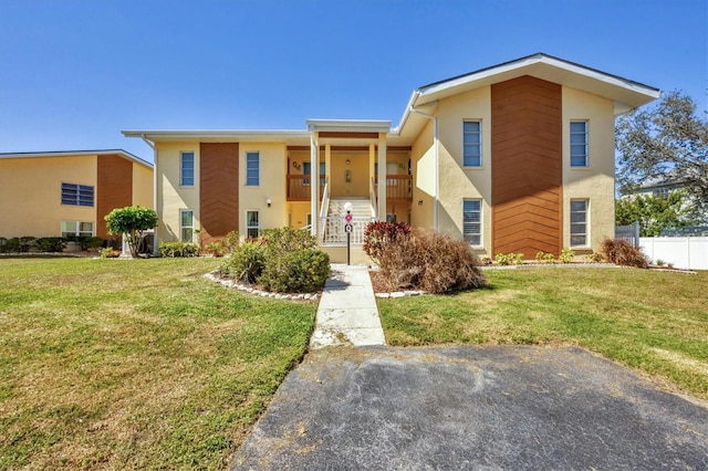 townhome / multi-family property featuring a front lawn, fence, and stucco siding