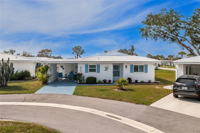 ranch-style house with stucco siding, a front lawn, concrete driveway, and a tiled roof