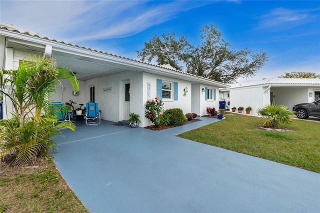 view of front of property with a carport, a front lawn, and stucco siding