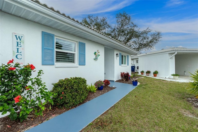 view of exterior entry with a yard and stucco siding