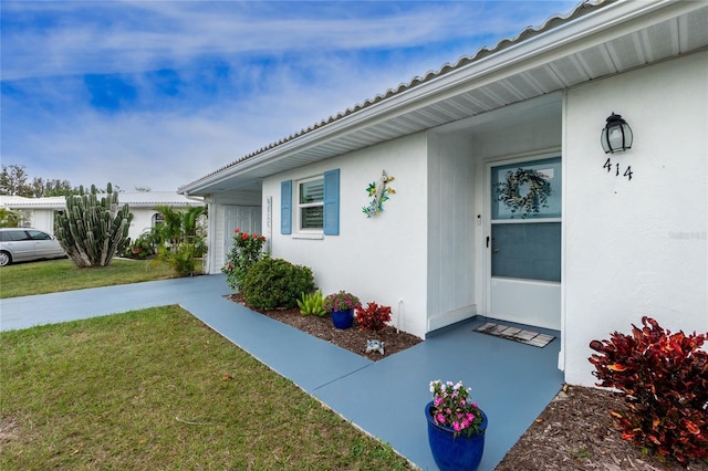 doorway to property featuring a yard and stucco siding