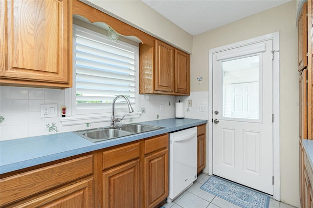 kitchen with light tile patterned floors, decorative backsplash, brown cabinetry, a sink, and dishwasher