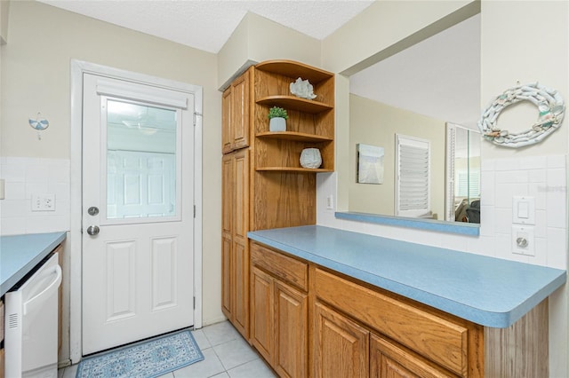 interior space with a textured ceiling, white dishwasher, light countertops, open shelves, and brown cabinetry