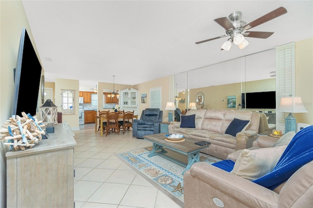 living room with light tile patterned floors, ceiling fan, and a textured ceiling