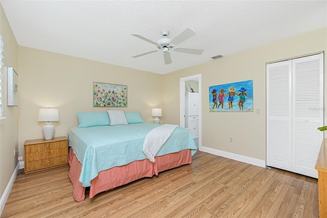 bedroom featuring baseboards, visible vents, a textured ceiling, light wood-style floors, and a closet