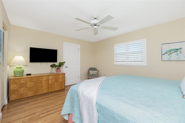 bedroom with light wood-type flooring, a closet, a ceiling fan, and a textured ceiling