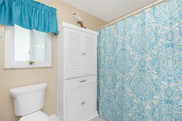 bathroom with a textured ceiling, a shower with shower curtain, and toilet