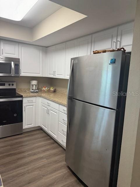 kitchen with stainless steel appliances, dark wood finished floors, light stone countertops, and white cabinets