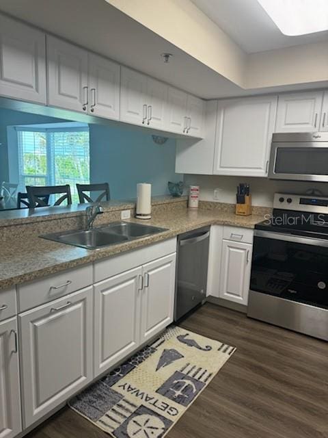 kitchen with dark wood-style flooring, white cabinetry, stainless steel appliances, and a sink