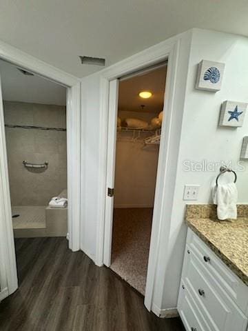 bathroom featuring a spacious closet, wood finished floors, vanity, and a shower stall