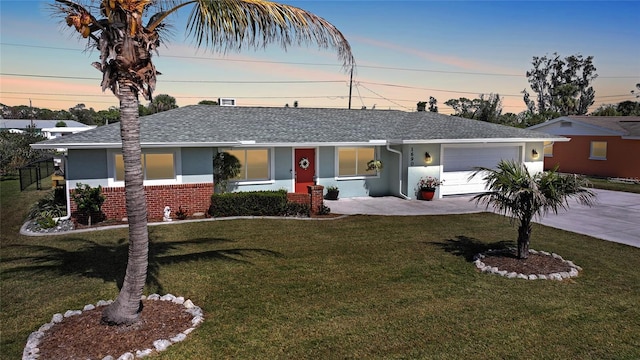 single story home with a shingled roof, concrete driveway, an attached garage, a front yard, and brick siding