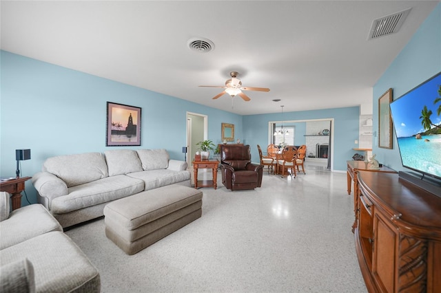 living area featuring speckled floor, visible vents, and a ceiling fan