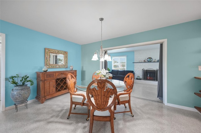 dining space with a chandelier, a brick fireplace, and baseboards