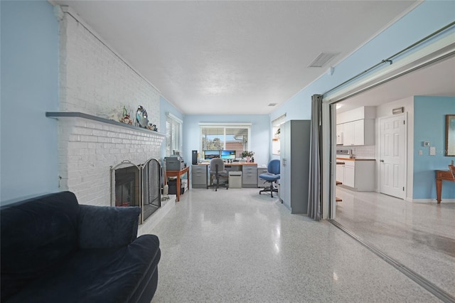 living area with light speckled floor, a brick fireplace, and visible vents