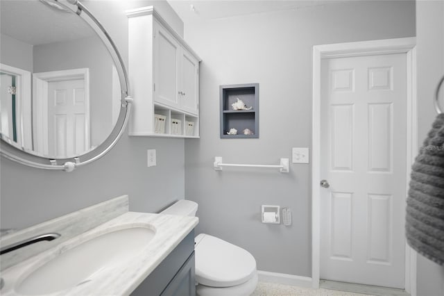 half bathroom with toilet, baseboards, and vanity