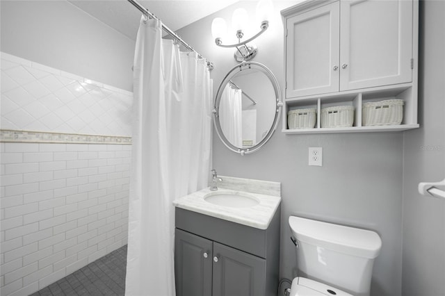 bathroom featuring a tile shower, vanity, and toilet