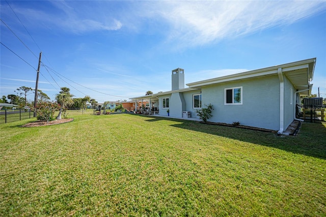 view of yard featuring central AC and fence