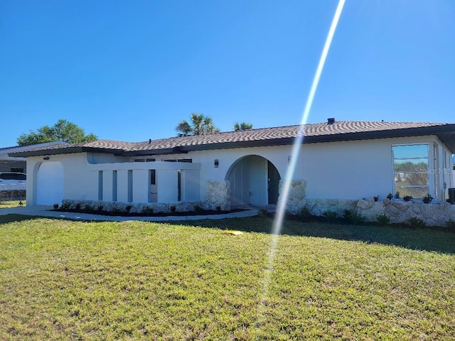 rear view of house featuring stucco siding, a lawn, and an attached garage