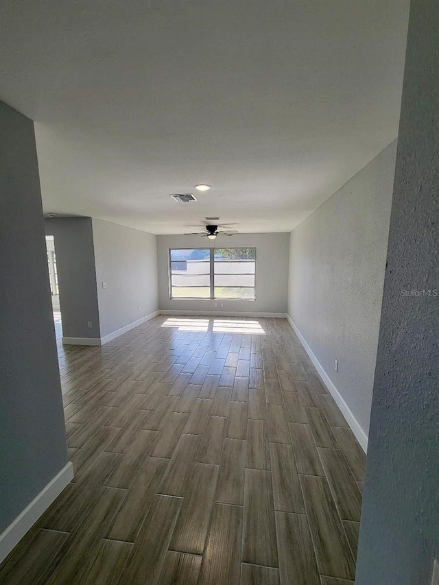 unfurnished room featuring visible vents, baseboards, ceiling fan, and wood tiled floor