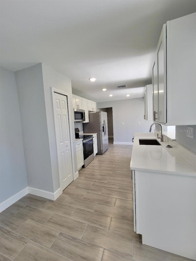 kitchen with visible vents, light countertops, appliances with stainless steel finishes, white cabinetry, and a sink