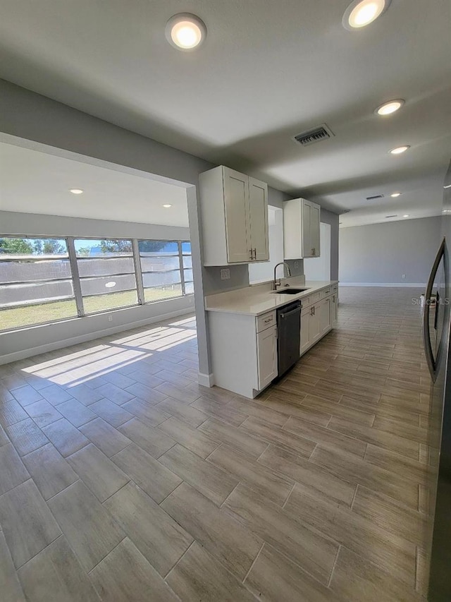 kitchen with visible vents, a sink, black dishwasher, refrigerator, and light countertops
