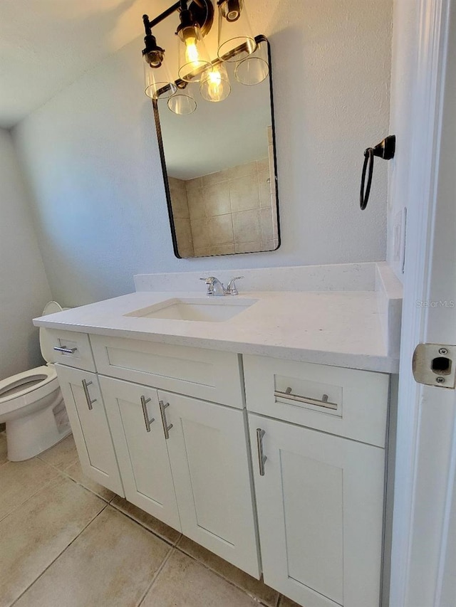 bathroom with tile patterned flooring, an inviting chandelier, toilet, and vanity
