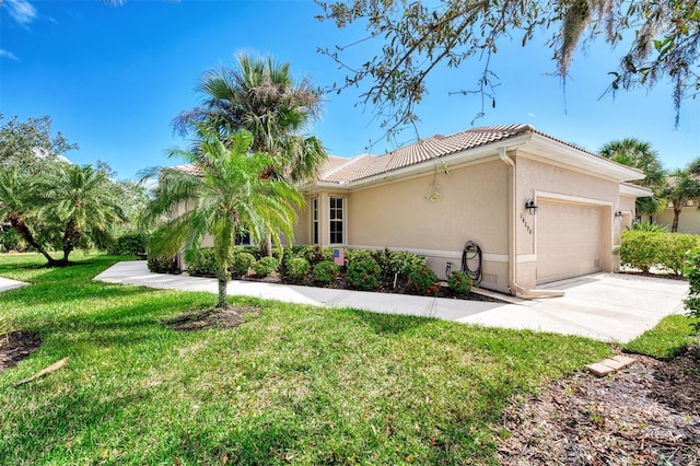 view of home's exterior featuring a garage, a tile roof, concrete driveway, a lawn, and stucco siding