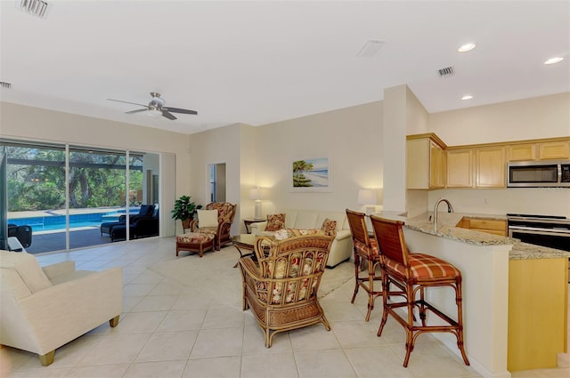 living room featuring light tile patterned flooring, ceiling fan, visible vents, and recessed lighting